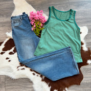 Green tank top and blue jeans on a cowhide rug with pink flowers.