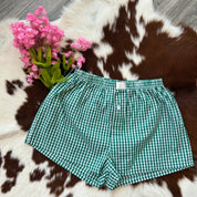 Green checkered shorts on a cowhide rug with pink flowers