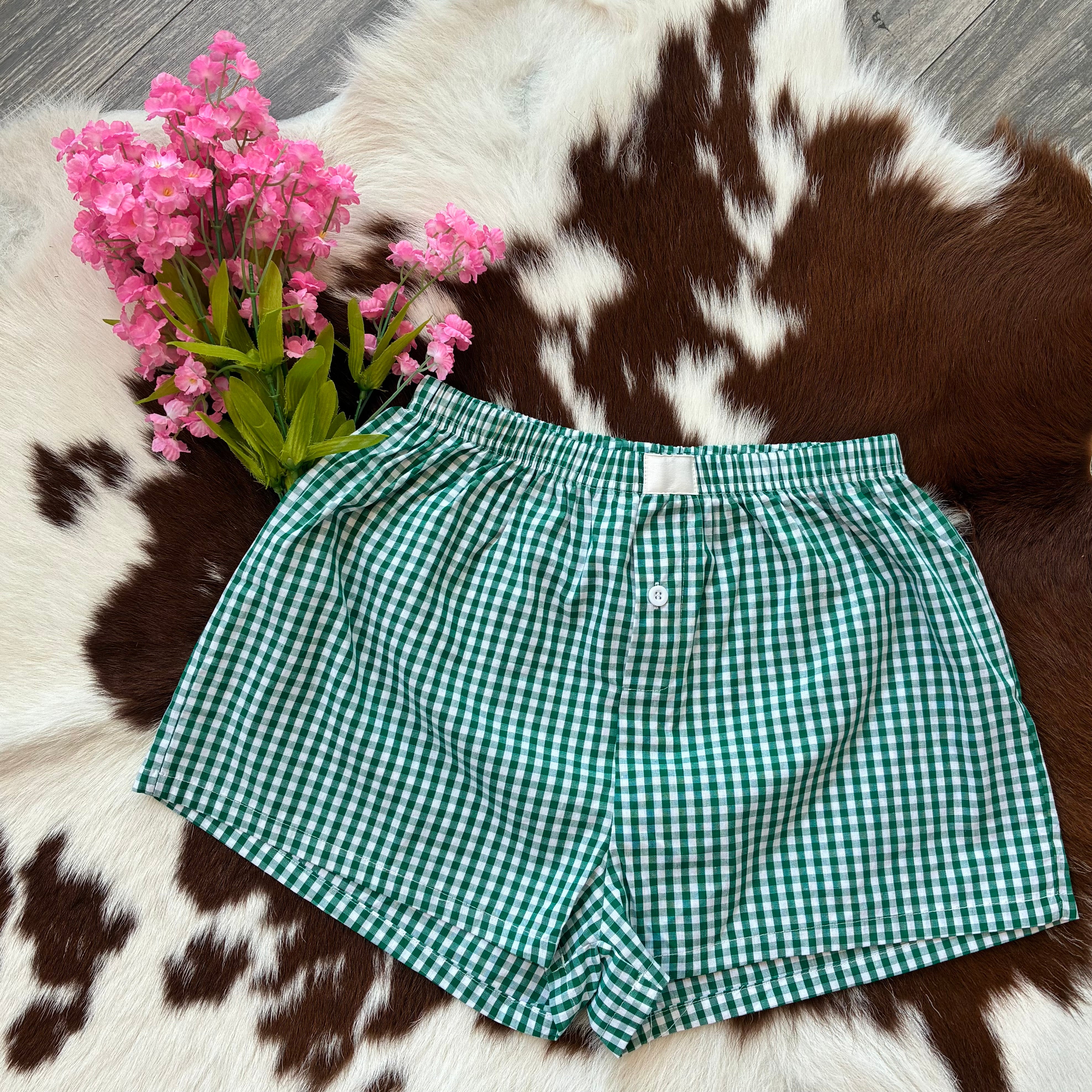 Green checkered shorts on a cowhide rug with pink flowers