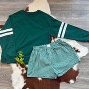 Green sweatshirt with white stripes and green checkered shorts on a cowhide rug.