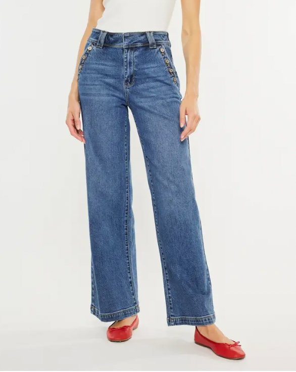 Model wearing high-waisted wide-leg jeans with button details, styled with a simple top and red flats, showcasing a chic and casual outfit.