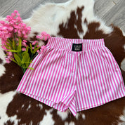 Pink and white striped shorts with 'Lulu Mac' label on a cowhide rug with pink flowers.