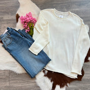 White sweater and blue jeans on a fur surface with pink flowers.