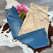 Beige tank top and blue jeans on a cowhide rug with pink flowers.