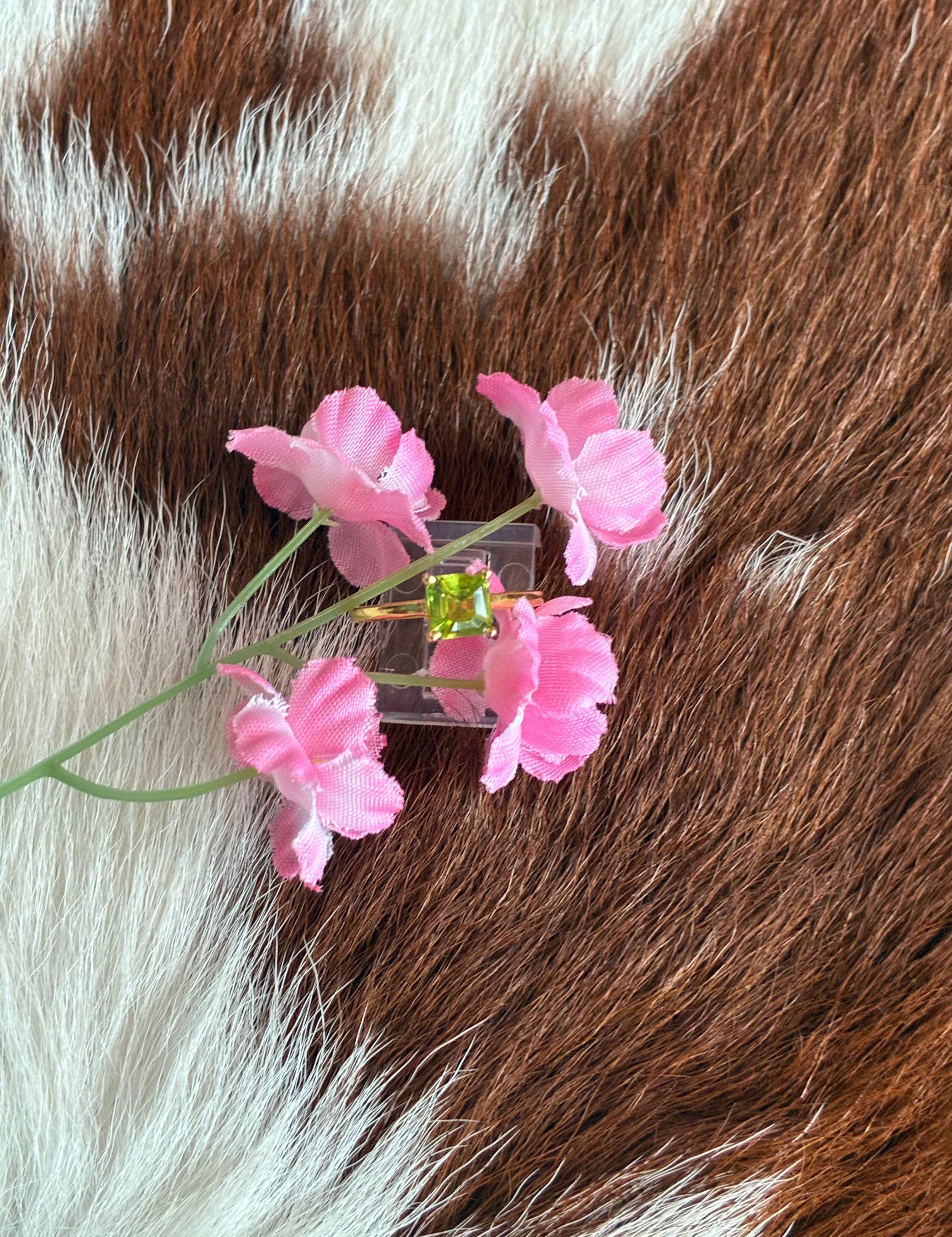 Pink flower hair clip with green gemstone on brown and white fur background