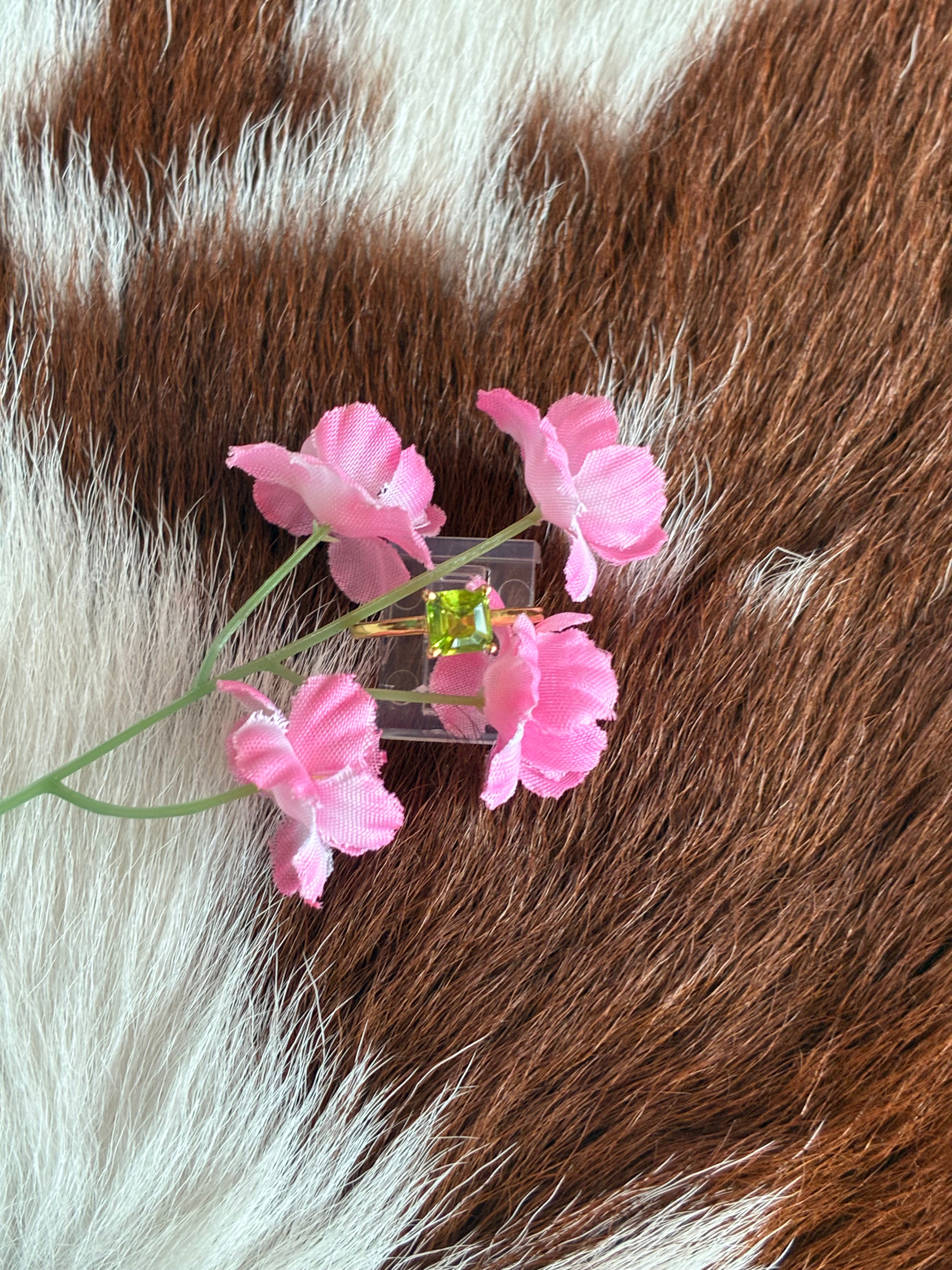 Pink flower hair clip with green gemstone on brown and white fur background