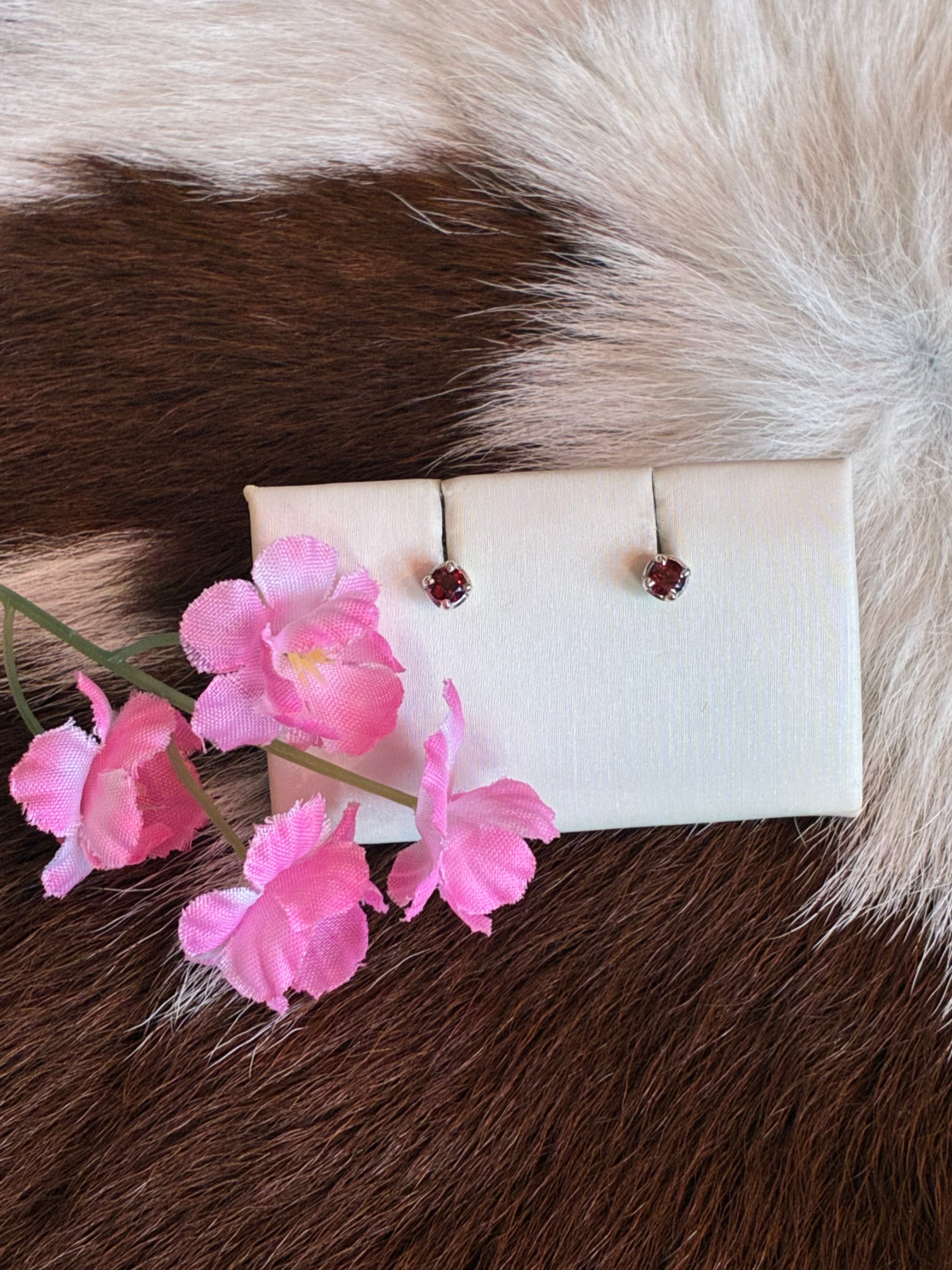 Pair of earrings on a white card with pink flowers on a fur background