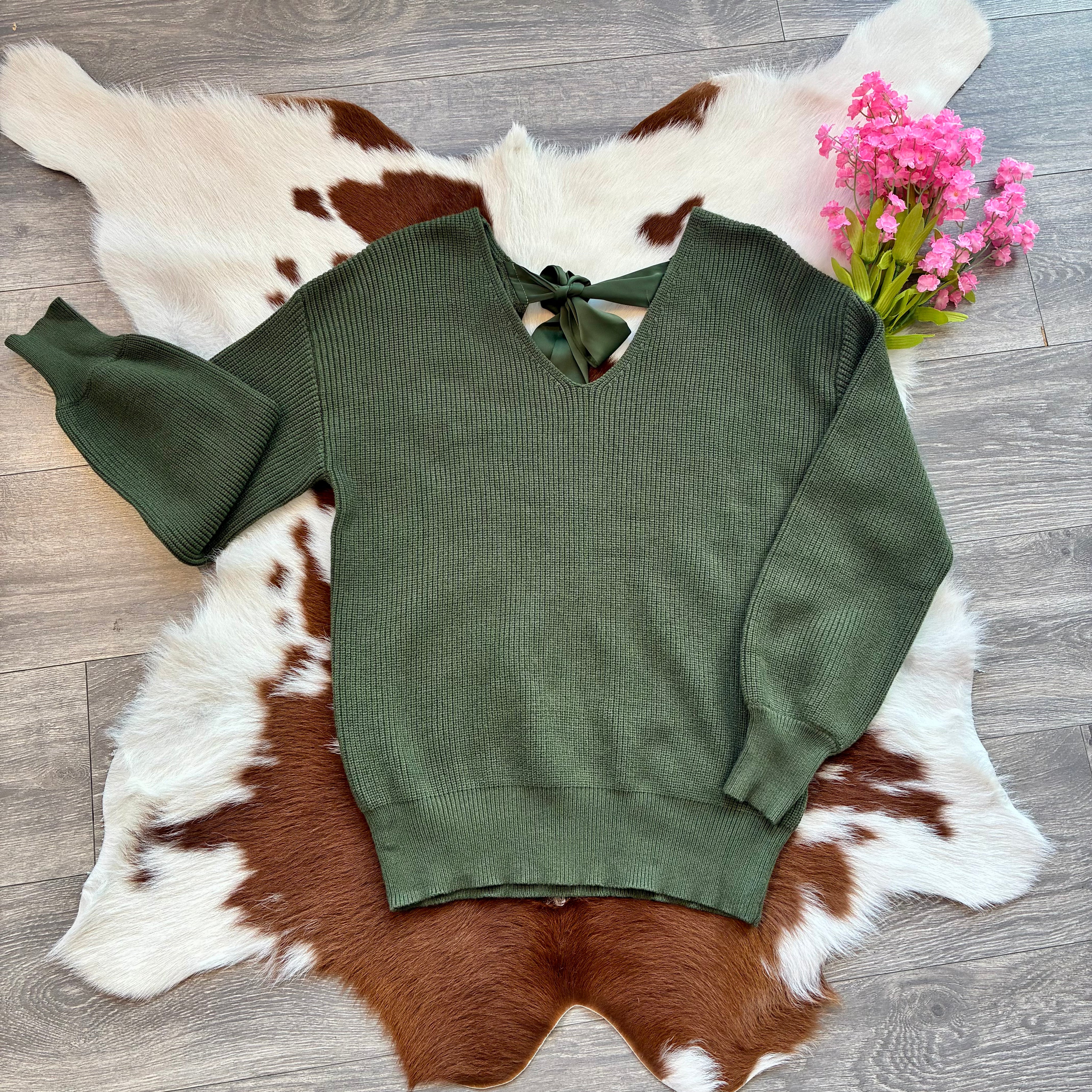 Green sweater on a cowhide rug with pink flowers