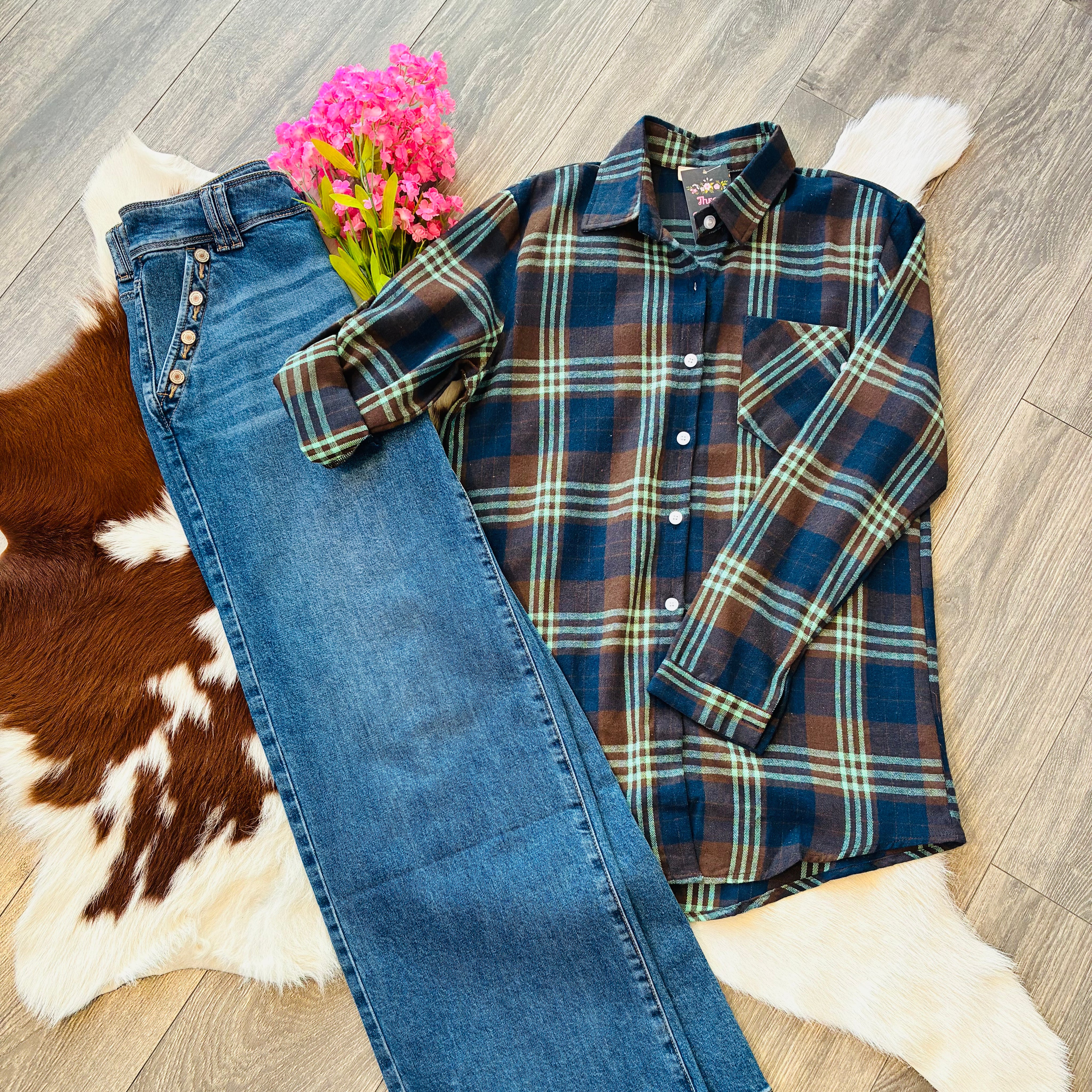 Plaid shirt and jeans on a wooden floor with a cowhide rug