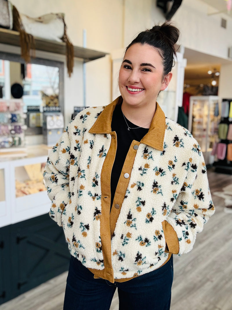Woman wearing a floral jacket with a brown collar in a store setting