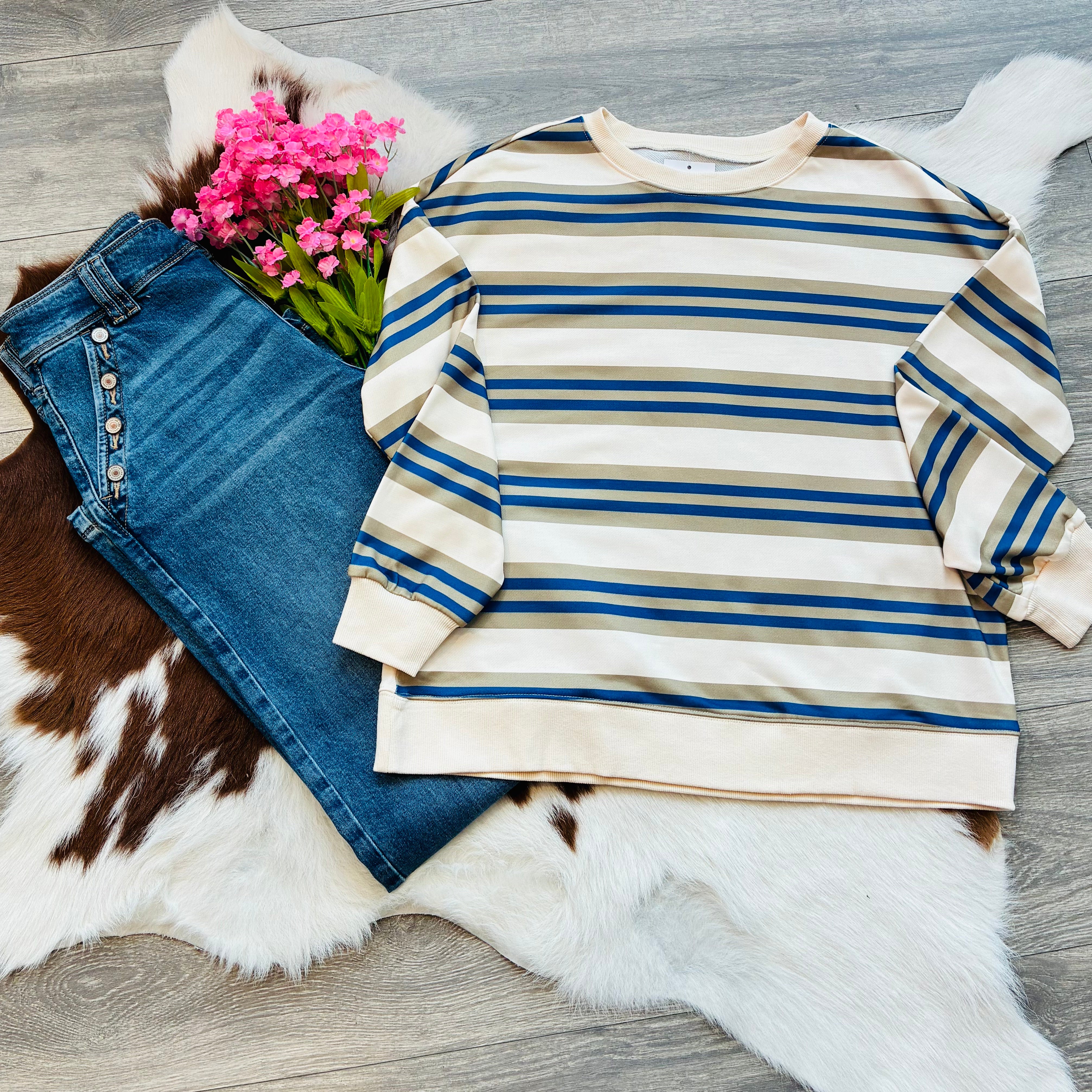 Striped sweater and jeans on a fur surface with pink flowers.