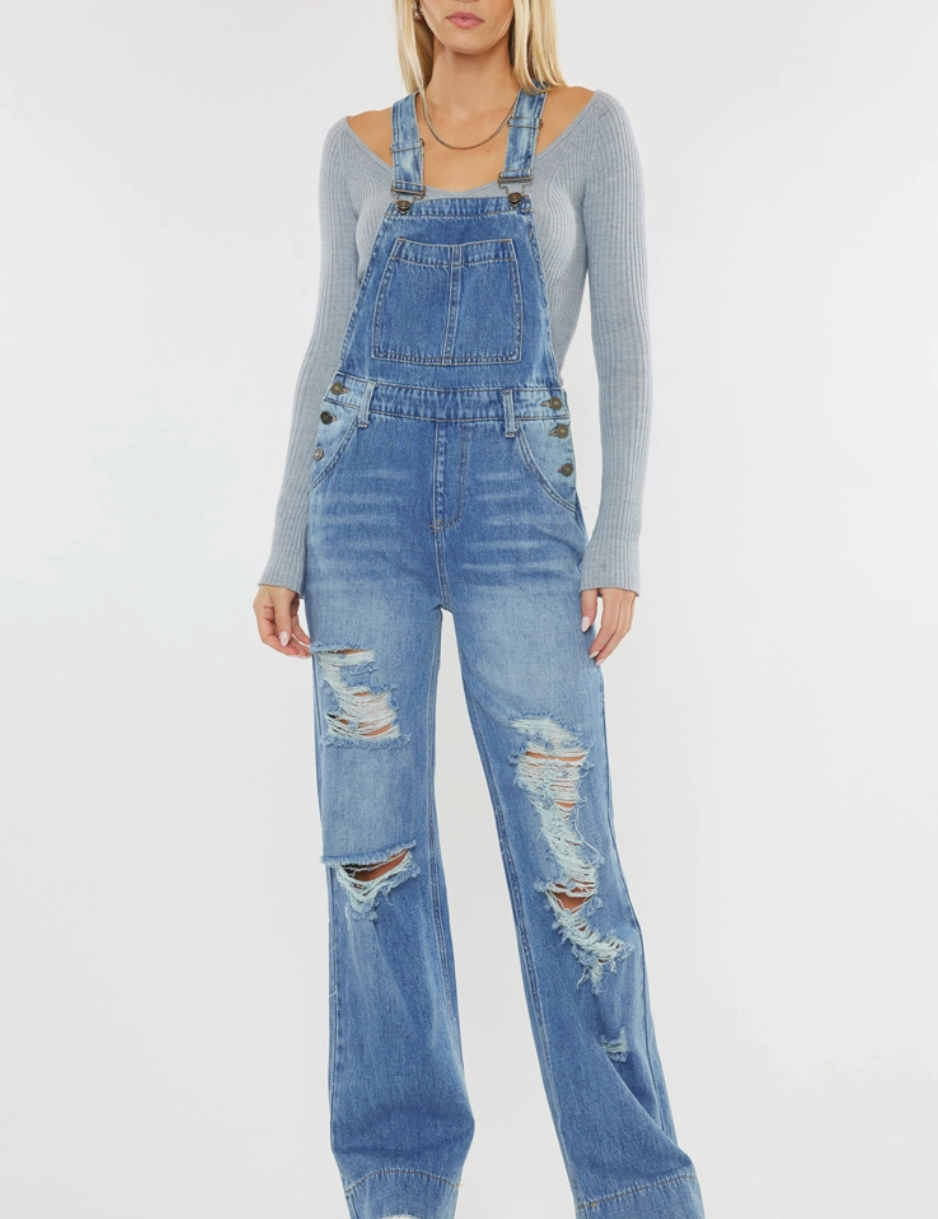 Women’s wide-leg denim overalls in medium stone wash with a relaxed fit, square neckline, adjustable shoulder straps, and front pocket details. Made from 100% cotton rigid, non-stretch denim for a vintage-inspired look. Perfect for casual and trendy outfits.