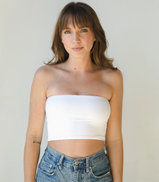 White strapless bandeau top with a form-fitting, stretchy design, styled with high-waisted denim jeans for a sleek and minimalistic look.