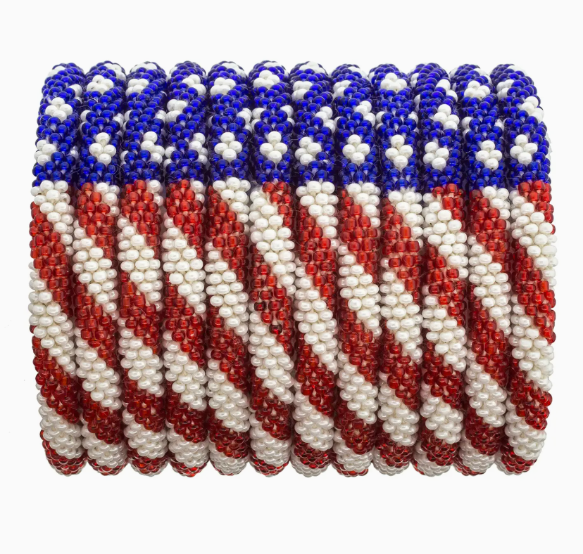 Close-up of a stack of 12 handcrafted Roll-On® Bracelets featuring red, white, and blue glass beads in a diagonal American flag-inspired pattern, symbolizing patriotic style and artisan craftsmanship.