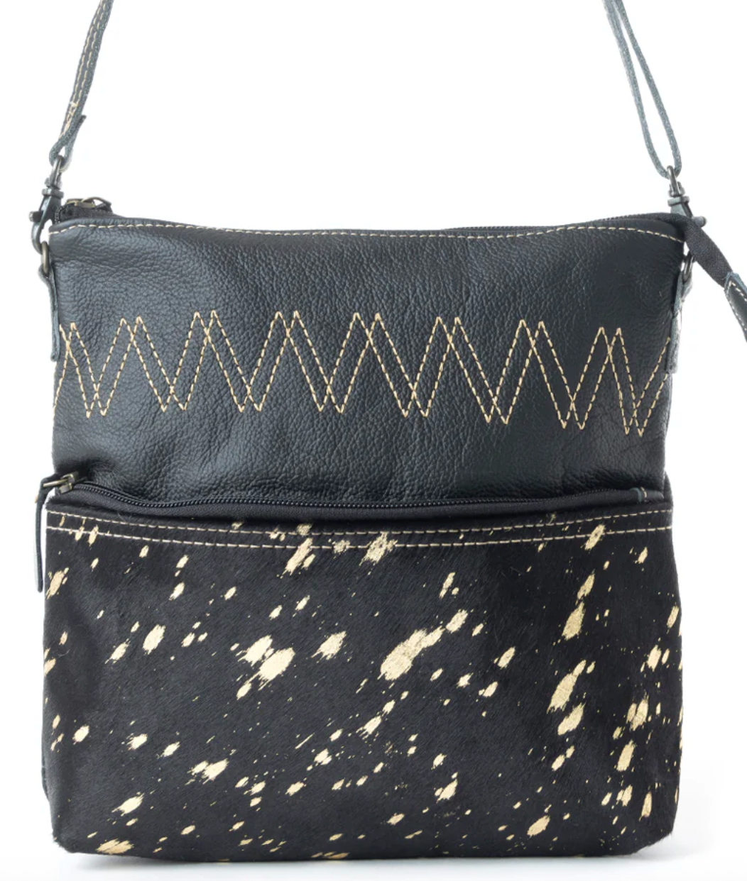 Black leather and hair-on-hide crossbody bag with gold splatter effect, zigzag stitching, and front zip pocket.