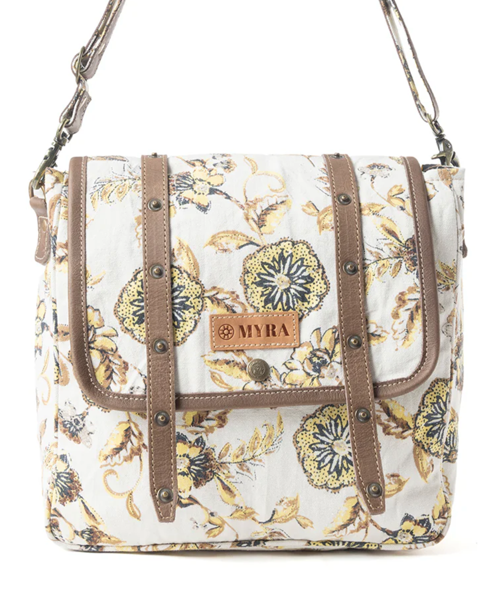Floral messenger bag with yellow and navy blooms on cream canvas, brown leather strap details, and vintage-style hardware.