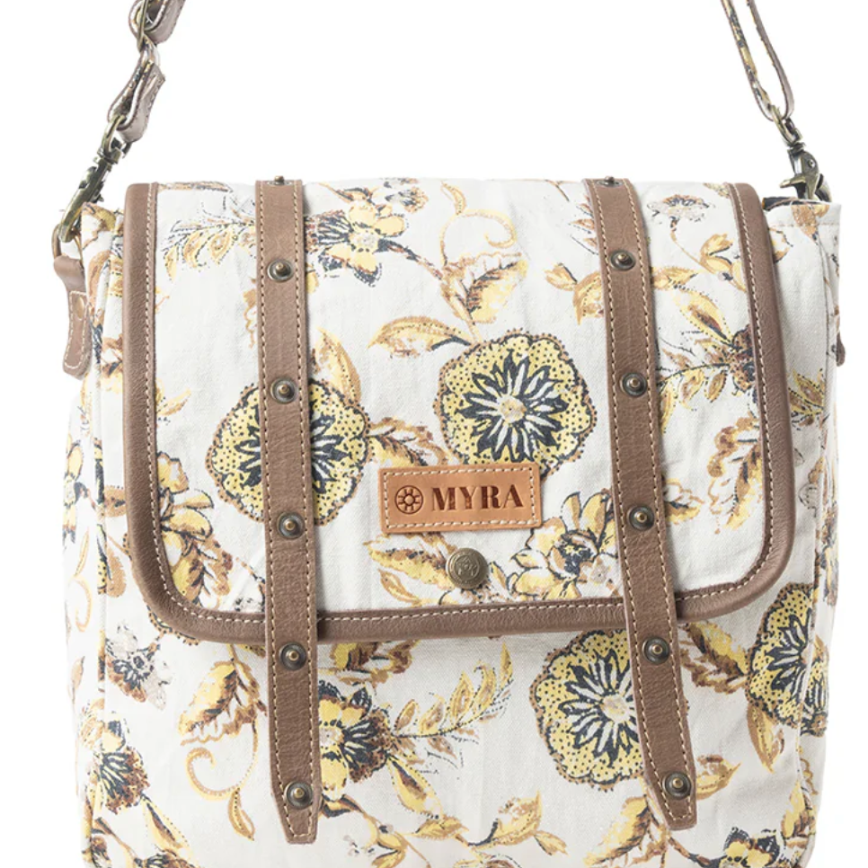 Floral messenger bag with yellow and navy blooms on cream canvas, brown leather strap details, and vintage-style hardware.