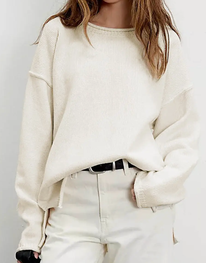 Cozy cream oversized sweater on a model, styled with high-waisted pants and a belt.