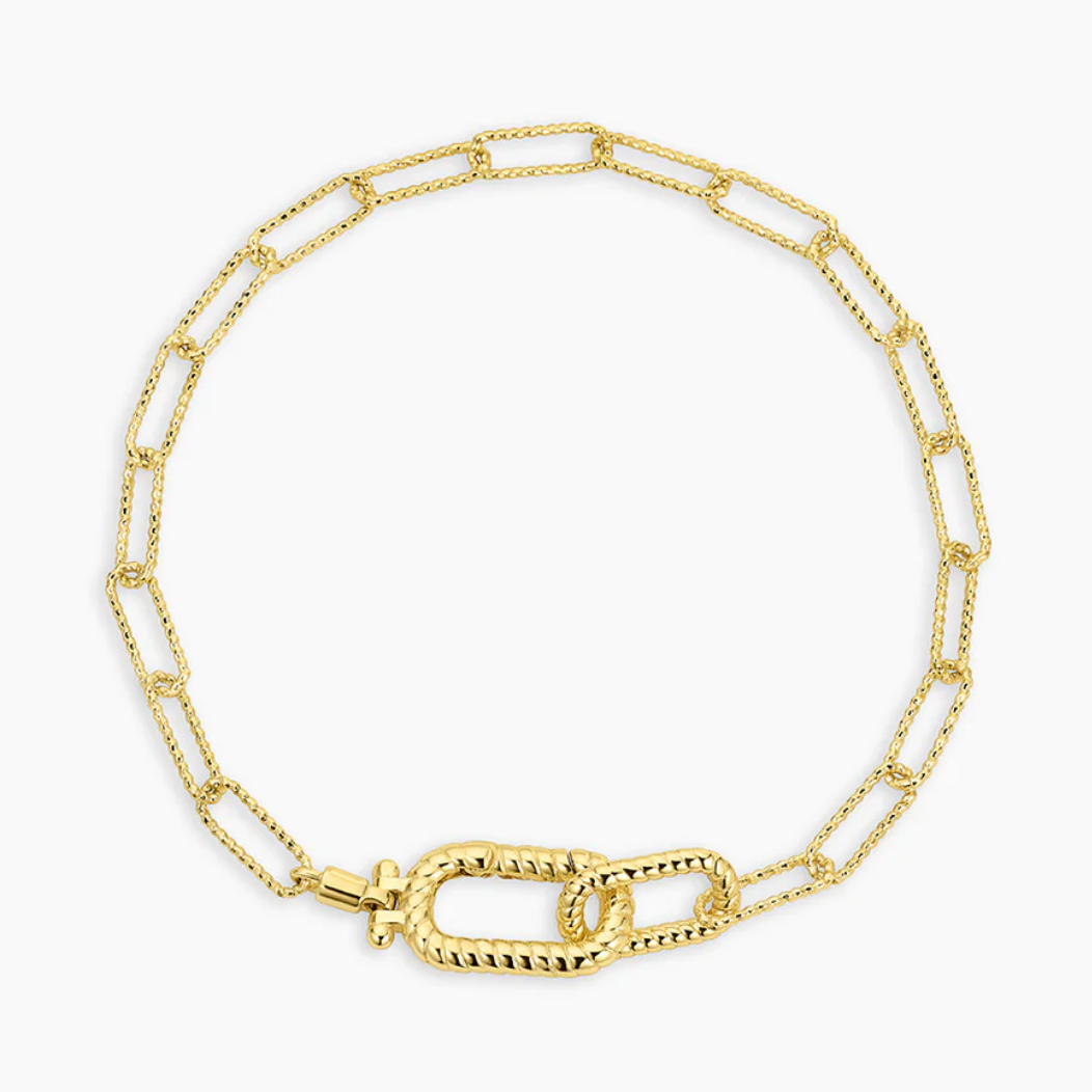 Close-up of a fashionable gold chain bracelet featuring a combination of elongated links and a decorative twisted toggle clasp. This unique design adds a sophisticated touch to any outfit, ideal for both casual and formal occasions.Let me know if you need any more help or additional information!