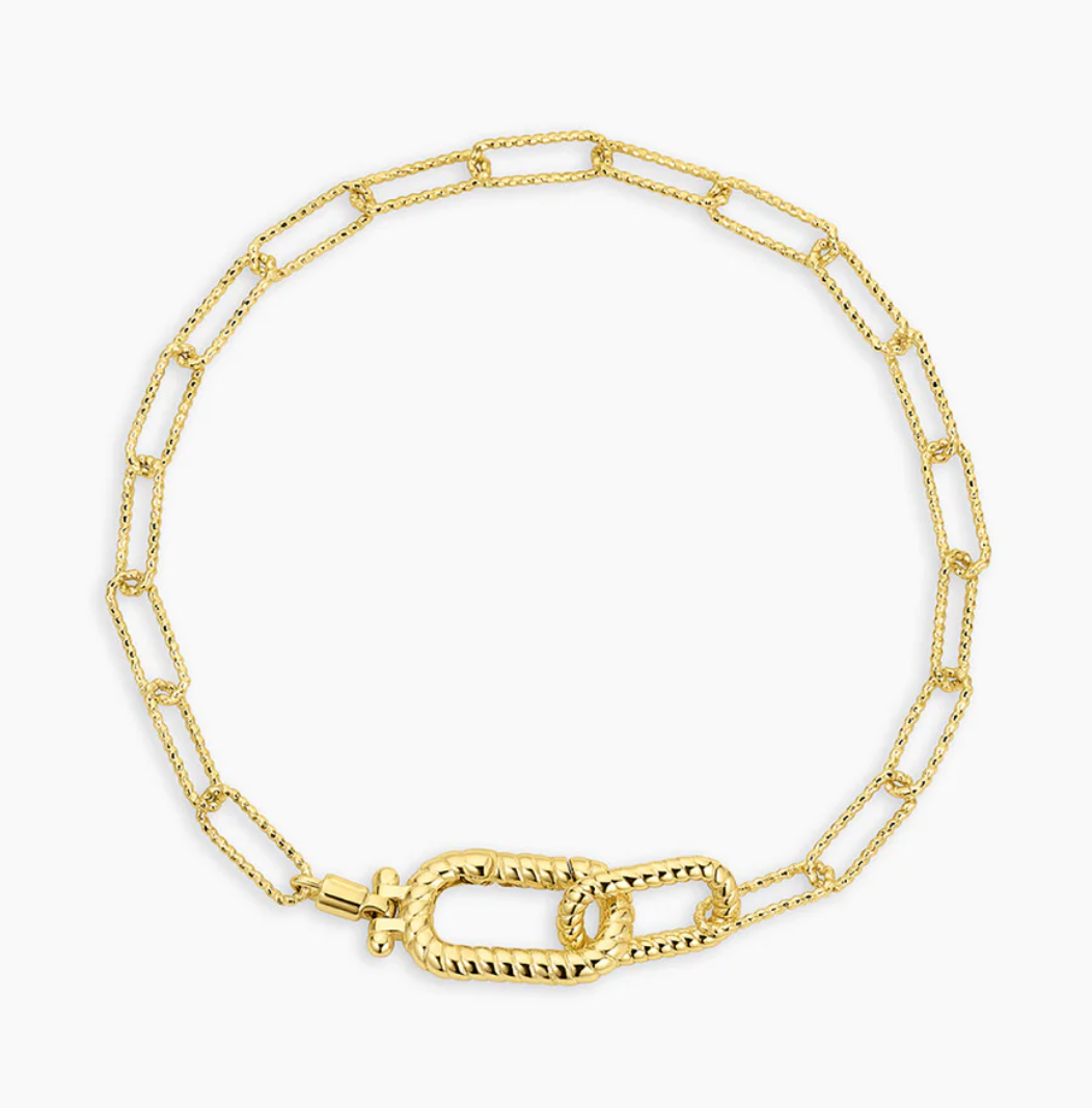 Close-up of a fashionable gold chain bracelet featuring a combination of elongated links and a decorative twisted toggle clasp. This unique design adds a sophisticated touch to any outfit, ideal for both casual and formal occasions.Let me know if you need any more help or additional information!