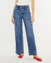 Model wearing high-waisted wide-leg jeans with button details, styled with a simple top and red flats, showcasing a chic and casual outfit.